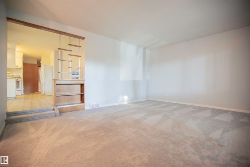 Carpeted living space with a decorative room divider featuring a built-in bookshelf - 11131 52 Street Nw, Edmonton, AB - Indoor Photo Showing Other Room