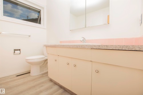 Bathroom featuring a functional vanity with integrated sink, coordinating countertop, and ample storage cabinetry - 11131 52 Street Nw, Edmonton, AB - Indoor Photo Showing Bathroom