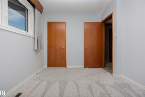 Light gray wall paint with white trim, gray patterned carpeting, and two wood-finish doors - 11131 52 Street Nw, Edmonton, AB - Indoor Photo Showing Other Room