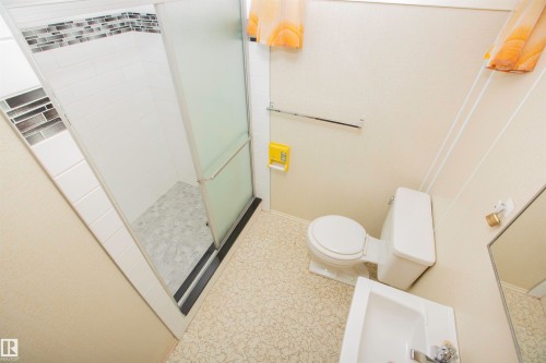 Shower with frosted sliding glass doors, white subway tile surround, and mosaic accent band - 11131 52 Street Nw, Edmonton, AB - Indoor Photo Showing Bathroom