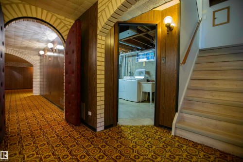 Arched brickwork accents a hallway featuring patterned carpet flooring and wood-paneled walls - 11131 52 Street Nw, Edmonton, AB - Indoor Photo Showing Other Room