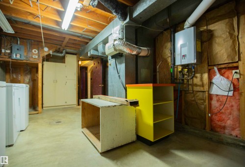 Basement utility area featuring exposed wood joists, concrete flooring, and a tankless water heater - 11131 52 Street Nw, Edmonton, AB - Indoor Photo Showing Basement