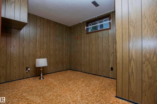 Room featuring wood-look paneling walls, textured gold carpeting, a drop ceiling with recessed ventilation, and a window with security bars - 11131 52 Street Nw, Edmonton, AB - Indoor Photo Showing Other Room