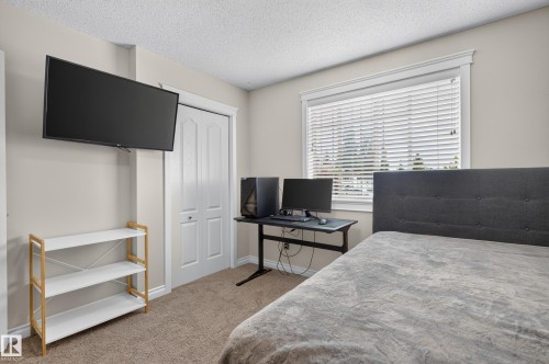 Carpeted room with a double bi-fold closet and a window featuring horizontal blinds - 12724 148 Avenue Nw, Edmonton, AB - Indoor Photo Showing Bedroom