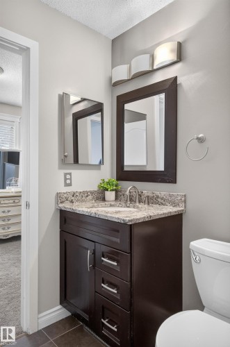 Dark wood-finish vanity with drawer storage, granite-style countertop, and integrated sink - 12724 148 Avenue Nw, Edmonton, AB - Indoor Photo Showing Bathroom