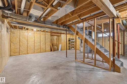 Unfinished basement with concrete flooring, exposed wooden joists, insulated walls, and a wooden staircase - 12724 148 Avenue Nw, Edmonton, AB - Indoor Photo Showing Basement
