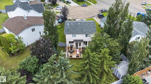 Rear exterior with a multi-level deck, surrounding mature trees, and a spacious lawn - 12724 148 Avenue Nw, Edmonton, AB - Outdoor With View