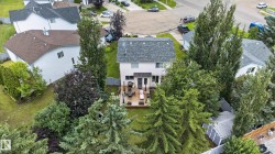 Rear exterior with a multi-level deck, surrounding mature trees, and a spacious lawn - 