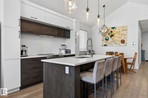 Modern kitchen featuring white and wood-finish cabinetry, a white subway tile backsplash, and an island with a white countertop - 45 Evermore Crescent, St. Albert, AB - Indoor Photo Showing Kitchen With Upgraded Kitchen