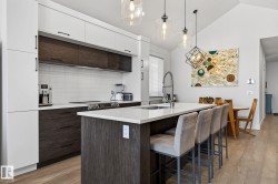 Modern kitchen featuring white and wood-finish cabinetry, a white subway tile backsplash, and an island with a white countertop - 