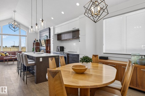 Open-concept living space featuring vaulted ceilings, a kitchen island with seating, a white subway tile backsplash, and wood-finish flooring - 45 Evermore Crescent, St. Albert, AB - Indoor Photo Showing Dining Room
