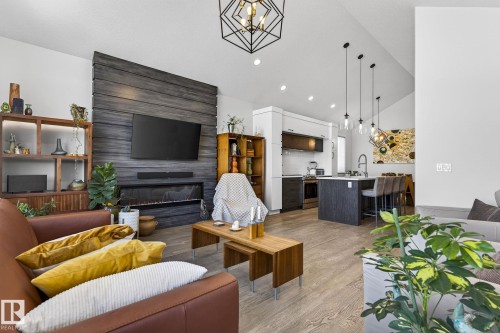 Vaulted ceilings, wood-finish flooring, and a linear electric fireplace with a wood-paneled accent wall - 45 Evermore Crescent, St. Albert, AB - Indoor Photo Showing Living Room With Fireplace