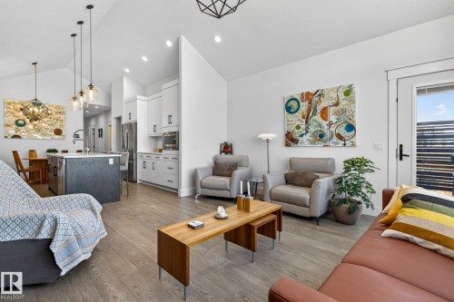 Vaulted ceilings, wood-finish flooring, white flat-panel cabinetry, stainless steel appliances, and a kitchen island with pendant lighting - 45 Evermore Crescent, St. Albert, AB - Indoor Photo Showing Living Room
