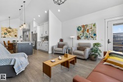 Vaulted ceilings, wood-finish flooring, white flat-panel cabinetry, stainless steel appliances, and a kitchen island with pendant lighting - 