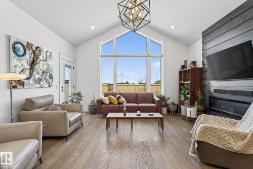 Vaulted ceilings with an angular window, wood-finish flooring, a linear electric fireplace, a horizontal slat accent wall, and recessed lighting - 45 Evermore Crescent, St. Albert, AB - Indoor Photo Showing Living Room With Fireplace