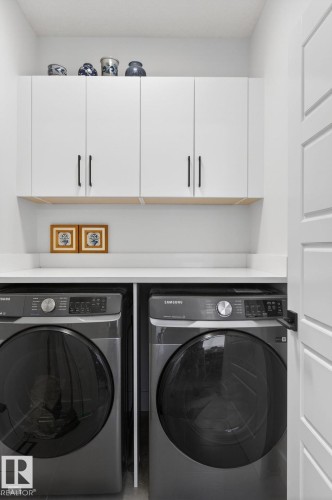 Built-in white cabinetry with black hardware, white countertop, and white interior door - 45 Evermore Crescent, St. Albert, AB - Indoor Photo Showing Laundry Room