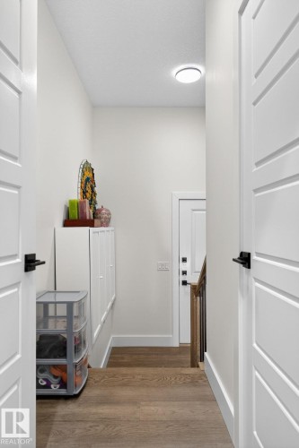 Wood-finish flooring, contemporary flat-panel doors with matte black hardware, recessed ceiling light, and a built-in storage bench - 45 Evermore Crescent, St. Albert, AB - Indoor Photo Showing Other Room