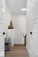 Wood-finish flooring, contemporary flat-panel doors with matte black hardware, recessed ceiling light, and a built-in storage bench - 