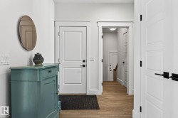 Light wood-finish flooring, white paneled doors with black hardware, recessed ceiling lighting - 