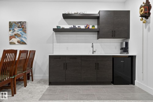 Wet bar featuring dark wood-finish cabinetry, white countertop, stainless steel sink, and white subway tile backsplash - 45 Evermore Crescent, St. Albert, AB - Indoor Photo Showing Other Room