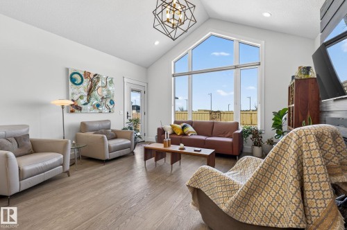 Bright, open living space showcasing soaring ceilings with geometric pendant lighting, expansive multi-pane windows framing expansive skyline vistas, and wide-plank wood-finish flooring throughout - 45 Evermore Crescent, St. Albert, AB - Indoor Photo Showing Living Room