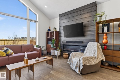 Vaulted ceiling, expansive windows, wood-finish flooring, built-in fireplace, and a wood-panel accent wall - 45 Evermore Crescent, St. Albert, AB - Indoor Photo Showing Living Room