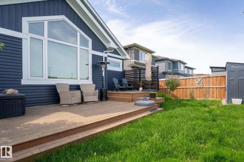 Expansive wood-finish deck with multiple levels, featuring a large trapezoidal window, dark-toned horizontal siding, and a partially fenced yard - 45 Evermore Crescent, St. Albert, AB - Outdoor