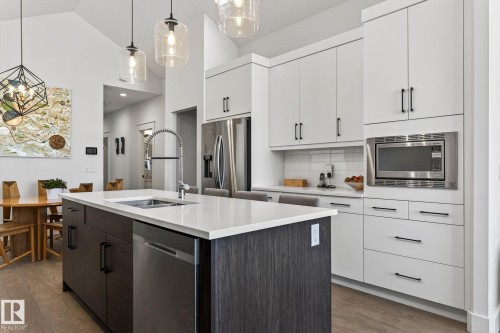Kitchen featuring a central island with an undermount sink, stainless steel appliances, white flat-panel cabinetry, and wood-finish flooring - 45 Evermore Crescent, St. Albert, AB - Indoor Photo Showing Kitchen With Double Sink With Upgraded Kitchen