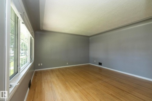Wood-finish flooring, light gray wall paint, white trim, and white-framed windows - 12322 94 Street Nw, Edmonton, AB - Indoor Photo Showing Other Room