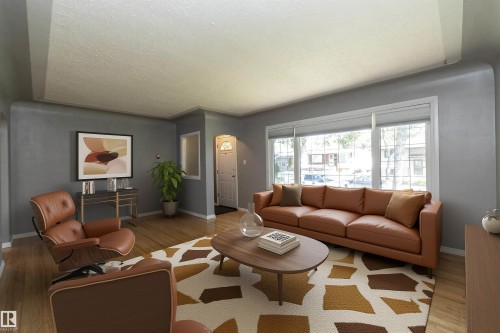 Hardwood flooring, expansive window, neutral wall paint, white trim, and a front entry door with a decorative glass insert - 12322 94 Street Nw, Edmonton, AB - Indoor Photo Showing Living Room