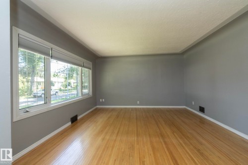 Hardwood flooring, painted walls, large picture windows, and white trim molding - 12322 94 Street Nw, Edmonton, AB - Indoor Photo Showing Other Room