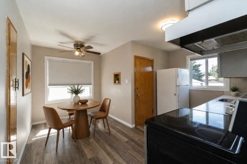 Dining area featuring wood-finish flooring, a ceiling fan with integrated lighting, and a window with blinds - 12322 94 Street Nw, Edmonton, AB - Indoor Photo Showing Dining Room