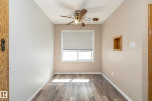 Wood-finish flooring with white trim and a neutral paint palette - 12322 94 Street Nw, Edmonton, AB - Indoor Photo Showing Other Room