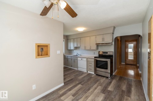 Kitchen featuring wood-finish flooring, light gray cabinetry, stainless steel range, and a white dishwasher - 12322 94 Street Nw, Edmonton, AB - Indoor Photo Showing Kitchen