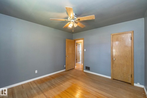 Wood-finish flooring, ceiling fan with integrated lighting, and painted walls - 12322 94 Street Nw, Edmonton, AB - Indoor Photo Showing Other Room