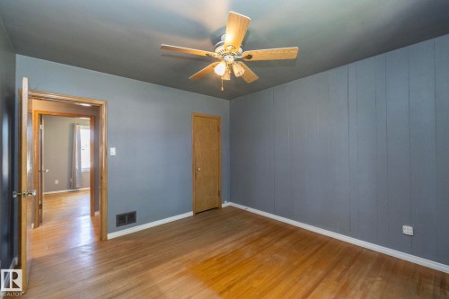 Light wood-finish flooring, paneled wall detailing, and a ceiling-mounted fan with integrated lighting - 12322 94 Street Nw, Edmonton, AB - Indoor Photo Showing Other Room