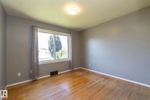 Wood-finish flooring, neutral gray walls, and white trim - 12322 94 Street Nw, Edmonton, AB - Indoor Photo Showing Other Room