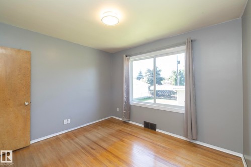 Wood-finish flooring, light gray wall paint, and a white trim package - 12322 94 Street Nw, Edmonton, AB - Indoor Photo Showing Other Room