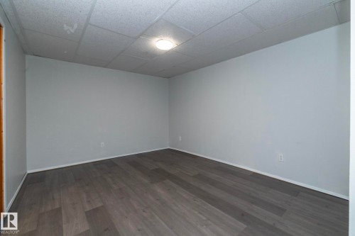 Gray wood-finish flooring, light gray painted walls, and a drop panel ceiling with recessed lighting - 12322 94 Street Nw, Edmonton, AB - Indoor Photo Showing Other Room