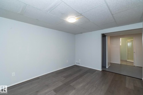 Spacious room featuring wood-finish flooring and light gray walls - 12322 94 Street Nw, Edmonton, AB - Indoor Photo Showing Other Room