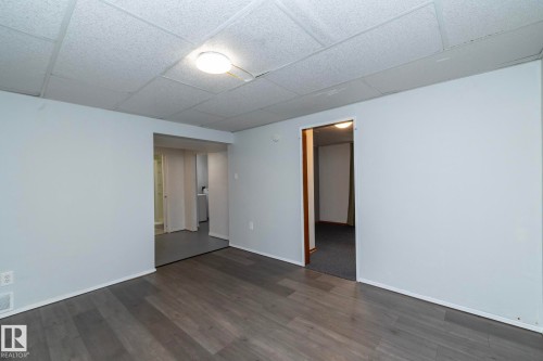 Light gray wall finish, wood-finish flooring, drop ceiling, and flush-mount ceiling light fixture - 12322 94 Street Nw, Edmonton, AB - Indoor Photo Showing Other Room