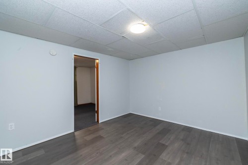 Wood-finish flooring with light gray walls, suspended ceiling, and a flush-mount ceiling light - 12322 94 Street Nw, Edmonton, AB - Indoor Photo Showing Other Room