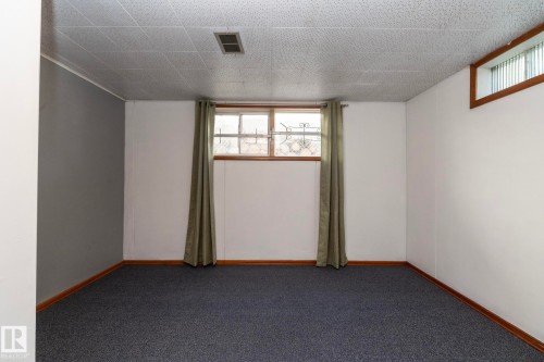 Carpeted room featuring a drop ceiling, white walls, and a single window with wood trim - 12322 94 Street Nw, Edmonton, AB - Indoor Photo Showing Other Room