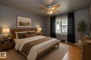 Hardwood flooring, painted paneled walls, ceiling fan with light fixture, window with drapes, and a dresser - 12322 94 Street Nw, Edmonton, AB  - Indoor Photo Showing Bedroom 