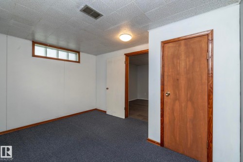 Recessed ceiling light, paneled walls, wood-framed window with glass block, wood-finish interior doors, and carpet flooring - 12322 94 Street Nw, Edmonton, AB - Indoor Photo Showing Other Room