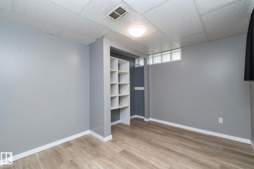 Built-in shelving, wood-finish flooring, drop ceiling, and glass block window - 12322 94 Street Nw, Edmonton, AB - Indoor Photo Showing Other Room