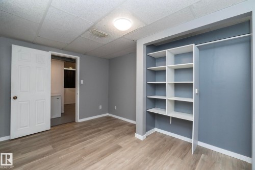 Wood-finish flooring with white trim, built-in shelving, and a panel ceiling - 12322 94 Street Nw, Edmonton, AB - Indoor