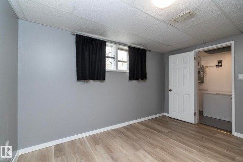 Light wood-finish flooring, neutral gray walls, and white trim - 12322 94 Street Nw, Edmonton, AB - Indoor Photo Showing Other Room