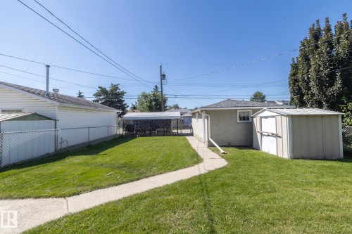 Expansive grass yard with a concrete pathway leading to a covered structure - 12322 94 Street Nw, Edmonton, AB - Outdoor
