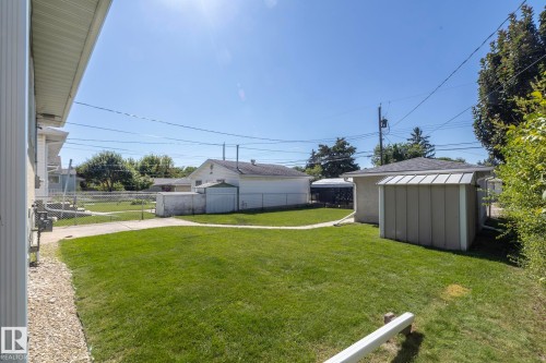 Expansive lawn with a concrete walkway, chain link fencing, a detached garage, and a shed - 12322 94 Street Nw, Edmonton, AB - Outdoor
